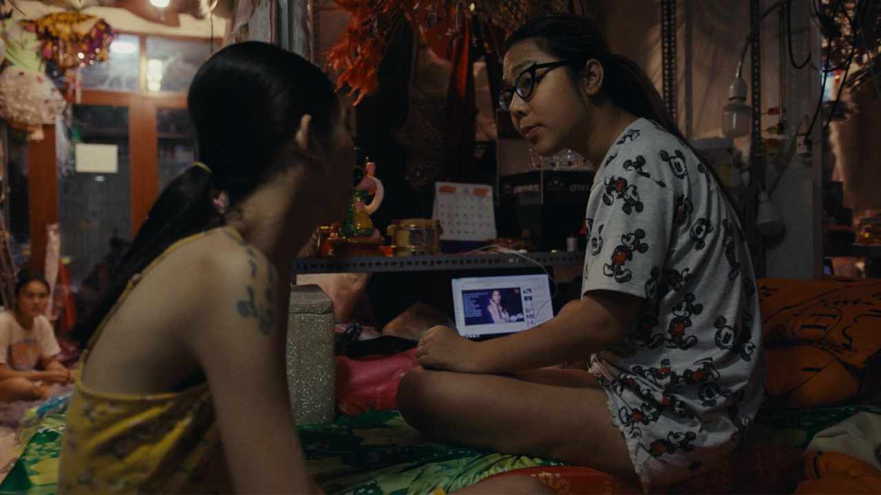 two young women talking with a laptop